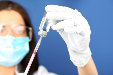 Ampule and syringe in hands of doctor on blue background