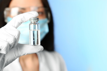 Ampule and syringe in hands of doctor on blue background