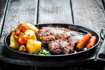 Roasted vegetables and steak with fresh herbs on barbecue dish