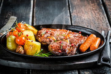 Roasted vegetables and steak with herbs on barbecue dish