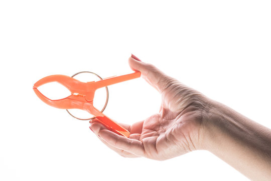 Female hand with manicure holds plastic clip on a white