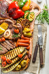 Fototapeta na wymiar Grilled vegetables and steak with herbs on wooden board