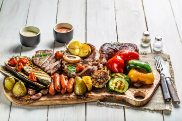 Fototapeta na wymiar Grilled steak and vegetables with salt on wooden board