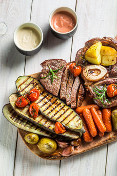 Roasted steak and vegetables with herbs on wooden board