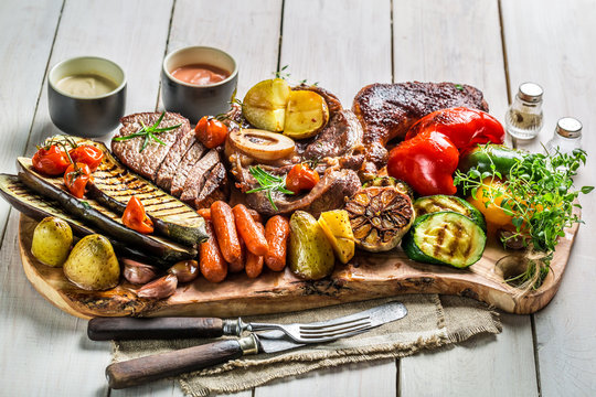 Grilled vegetables and steak with salt on white table