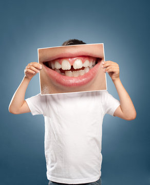 kid holding a picture of a mouth smiling