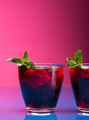 Raspberry and blackberry cocktail with mint garnish. Studio shot