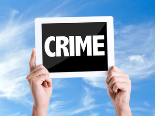 Tablet pc with text Crime with sky background