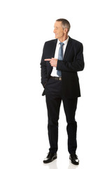 Full length businessman pointing to the left