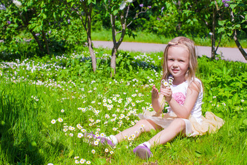 Little adorable girl enjoying beautiful day in blooming garden