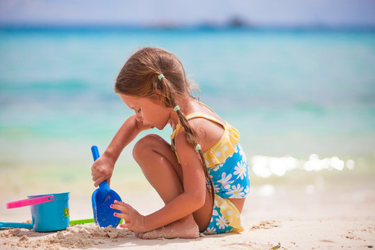 Little girl playing with beach toys during tropical vacation