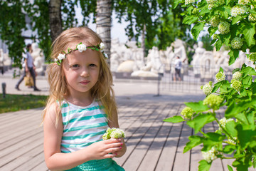 Little adorable girl near white flowers in the garden