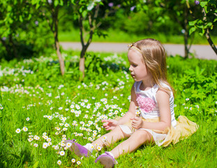 Little adorable girl enjoying beautiful day in blooming garden