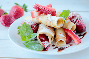Pancakes with strawberry and chocolate topping and castor sugar
