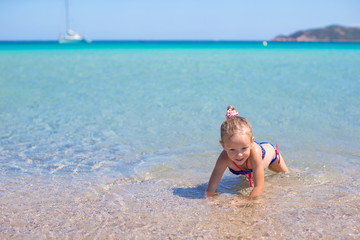 Adorable little girl have fun at shallow water on tropical beach