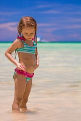 Adorable little girl having fun at shallow water on beach