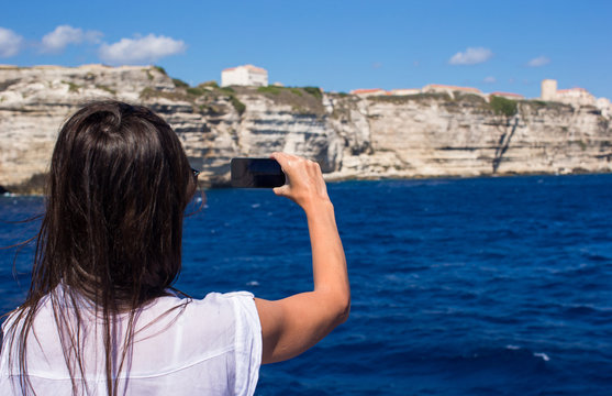 Girl taking pictures on a phone in Bonifacio, Corsica, France