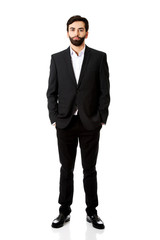 Smiling businessman with hands in pockets.