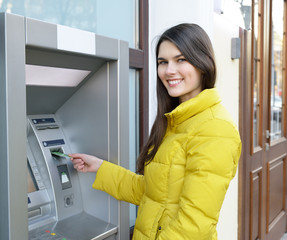 Fototapeta na wymiar Young woman withdrawing money from credit card at ATM