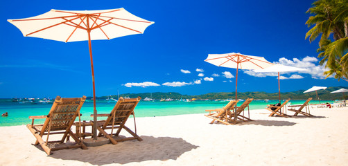 Fototapeta na wymiar Beach chairs and umbrellas on exotic tropical white sandy beach