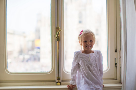 Adorable little girl looking out the window at Duomo, Milan