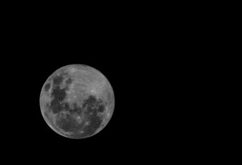 Full moon over dark black sky at night .