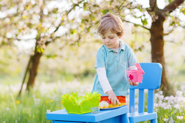 Adorable little boy playinig and painting colorful eggs