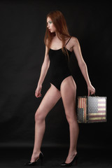 Beautiful woman in a black bodysuit posing on a black background
