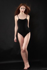 Fototapeta na wymiar Beautiful woman in a black bodysuit posing on a black background