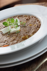 Plate of lentil soup with feta cheese cubes and fresh oregano.
