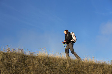 Female backpacker ascends steep hill