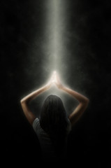 Portrait einer meditierenden Frau in einem Lichtstrahl