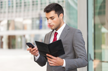 Businessman using his mobile phone while holding an agenda