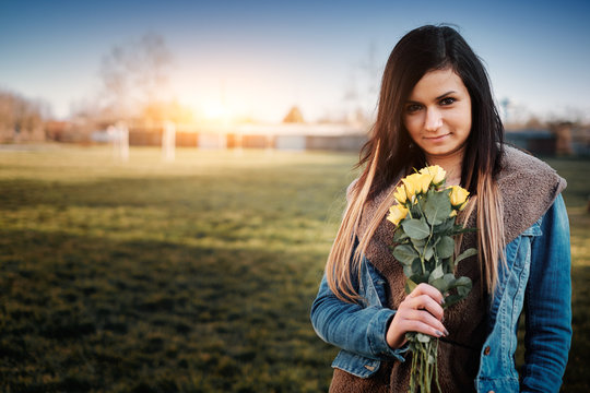 Attractive Young Woman With Yellow Rose In The Park