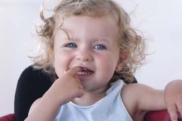 Naklejka premium Closeup of a baby's face with a finger in her mouth