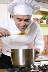 Chef with a spoon in the hand, smelling the food