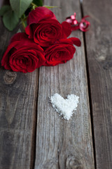 three red roses on rustic table