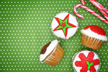 Festive Christmas cupcakes and candy canes on green background