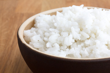 Rustic bowl of white rice on wood surface. Detail.