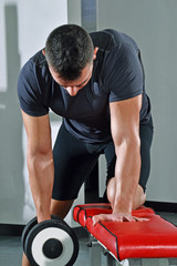 Fototapeta na wymiar Hombre deportista entrenando espalda con pesas en gimnasio.
