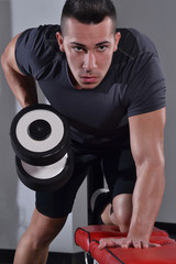 Hombre fuerte entrenando espalda con pesas en un gimnasio.