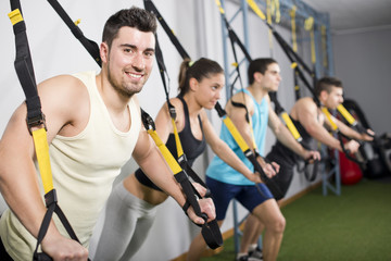Fototapeta na wymiar People at gym doing trx exercises