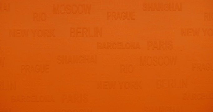 A closer shot of an orange background with world famous cities on it - the shot moves from the bottom to the top