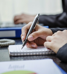 Closeup of businesswoman writing on her note book