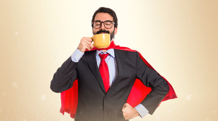 Businessman dressed like superhero drinking coffee