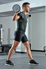 Hombre fuerte deportista entrenando piernas en gimnasio.