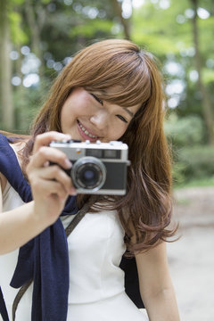 A woman in a Kyoto park holding a camera, preparing to take pictures.