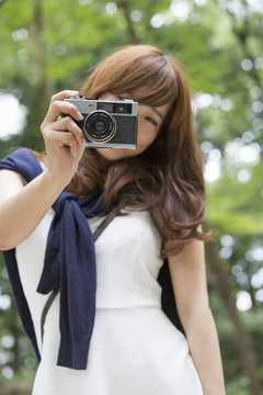 A woman in a Kyoto park holding a camera, preparing to take pictures.