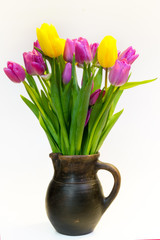 Bouquet of violet and yellow tulips in an old clay pot