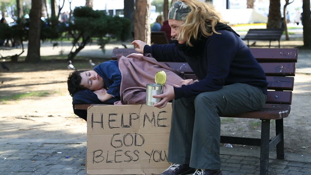 Homeless, sick family begging on a park bench